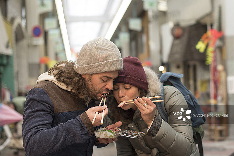情侣在大阪道顿堀用筷子一起吃寿司图片素材