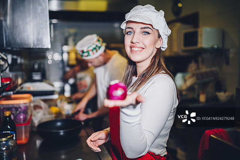 女人在餐厅厨房切洋葱准备意大利菜图片素材