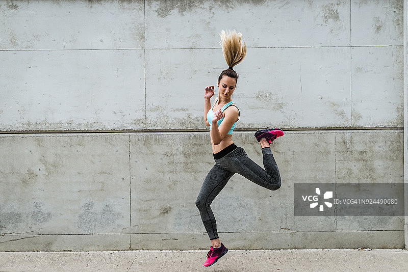 穿着运动服跳跃的健壮女人图片素材