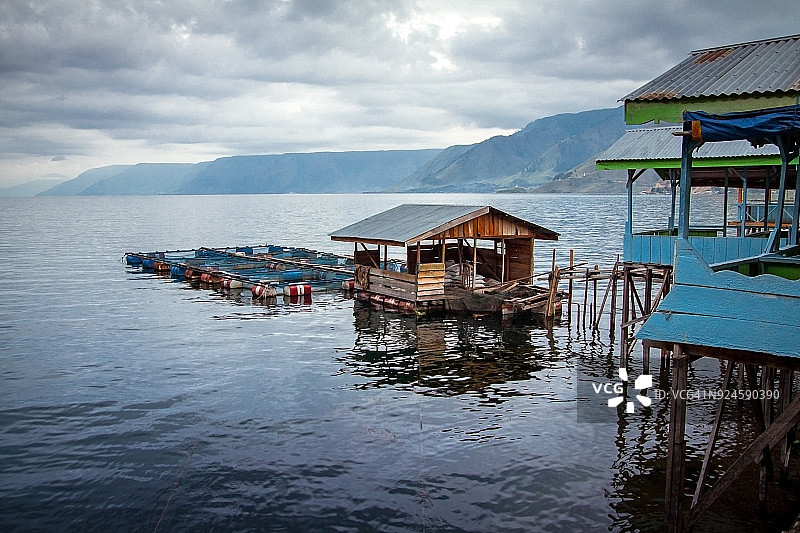 多巴火山湖上的养鱼场，背景是山景图片素材