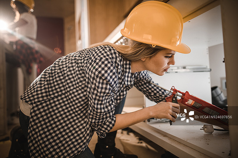 正在进行家居装修的使用填缝枪的女工人图片素材