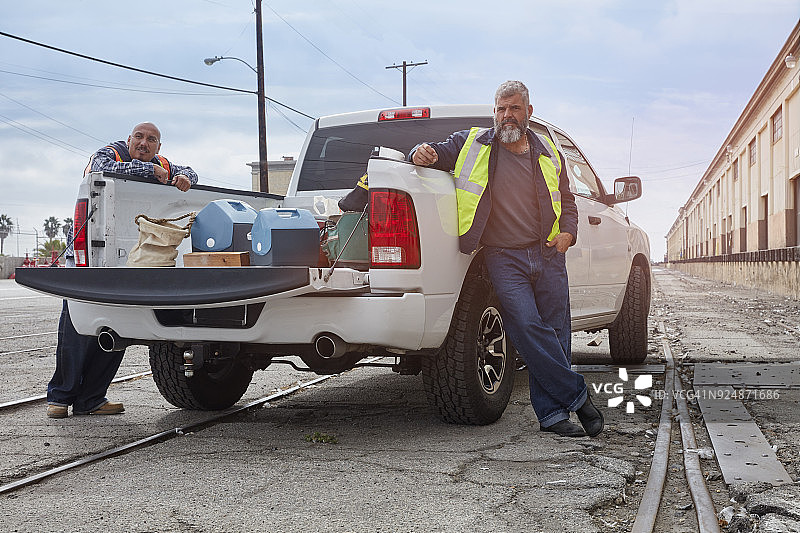 建筑工人在皮卡车旁等候。图片素材
