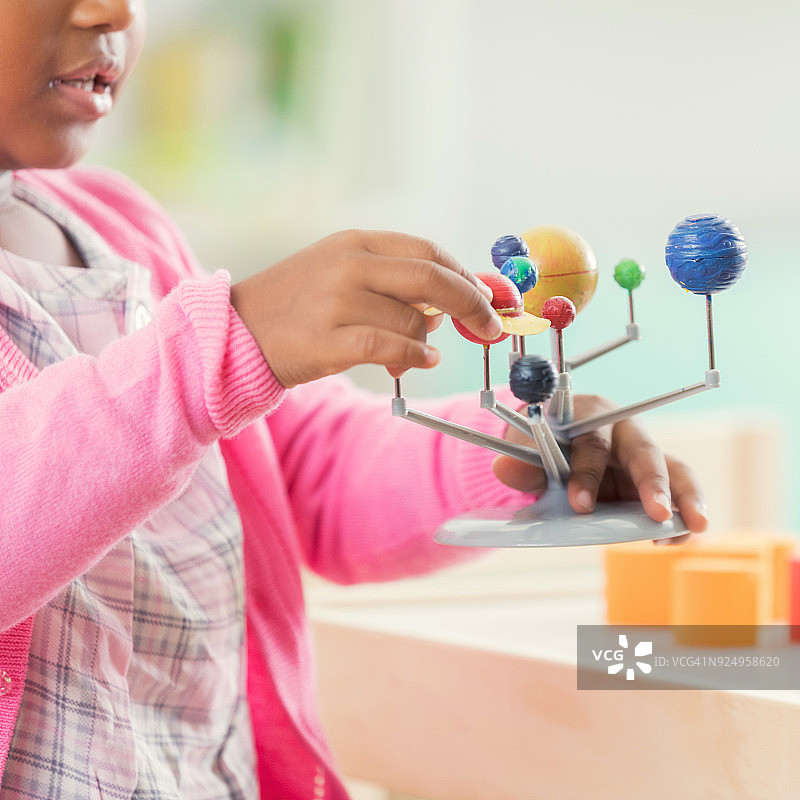 学龄前小女孩在课堂上学习太阳系模型图片素材