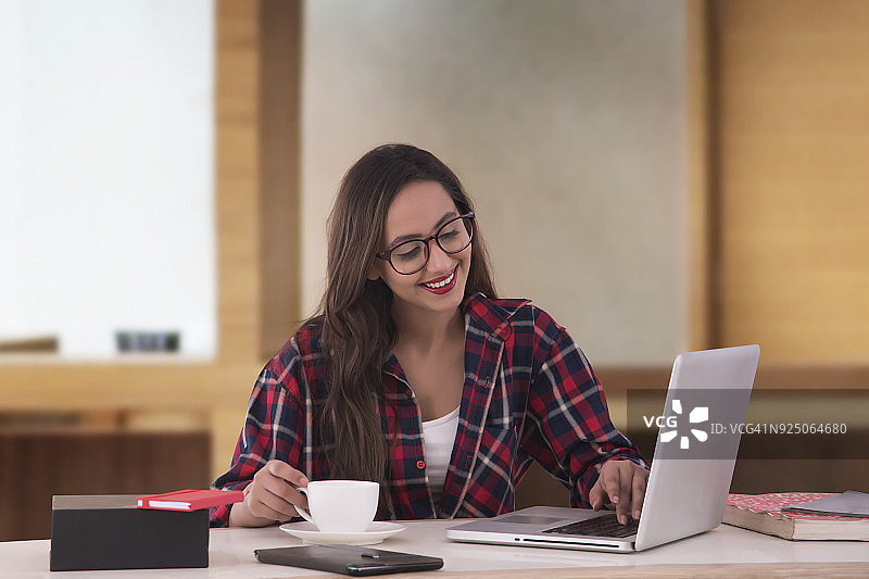 有魅力的年轻女商人在办公室喝咖啡工作图片素材