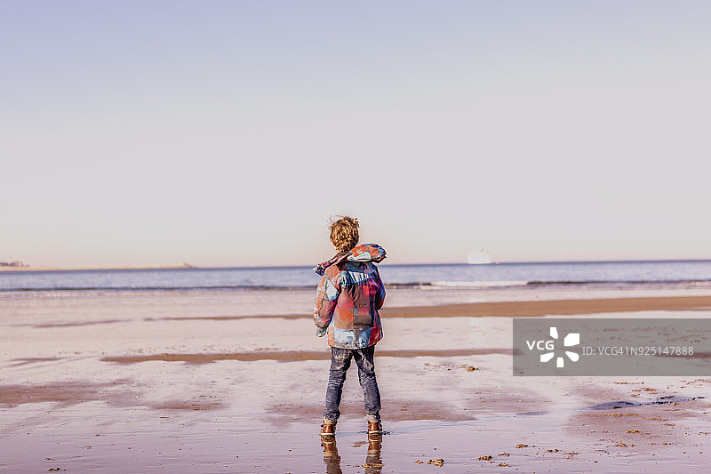 沙滩上穿雨衣的小男孩背影图片素材
