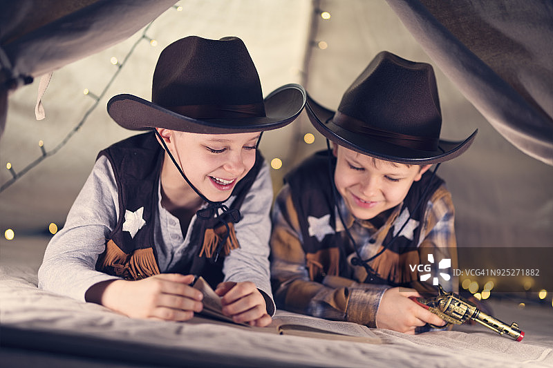 阅读牛仔故事书的快乐小男孩们图片素材