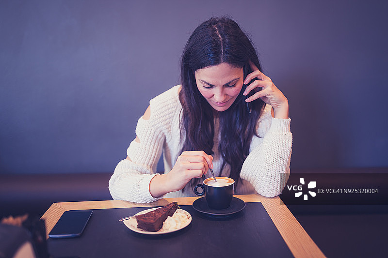 年轻女人在咖啡馆享用咖啡并使用智能手机图片素材
