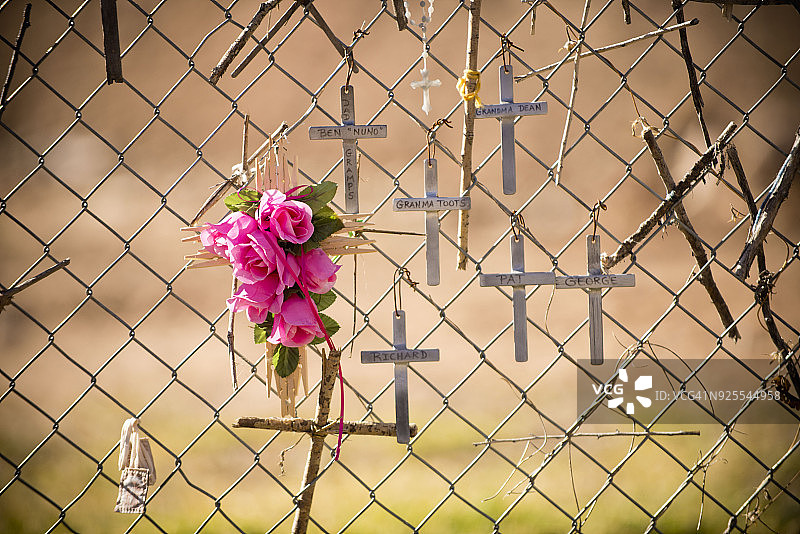 纪念围栏上悬挂的十字架和鲜花图片素材