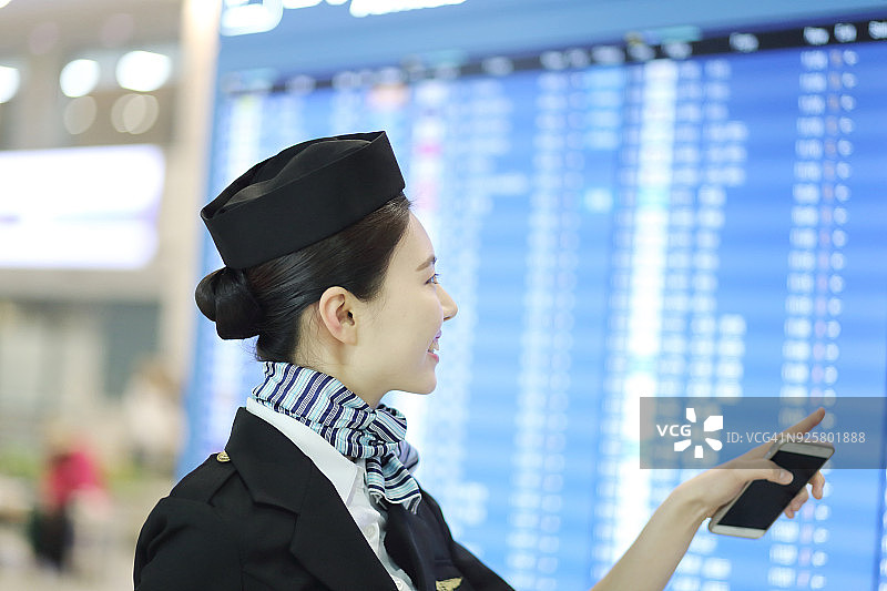空乘人员站在到港和离港信息板前图片素材