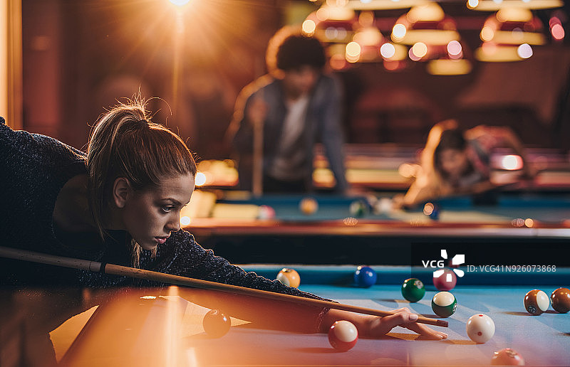 年轻专注的女子在酒吧打斯诺克图片素材