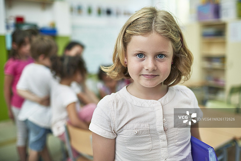 在学校里与同学们在一起的微笑女孩肖像图片素材
