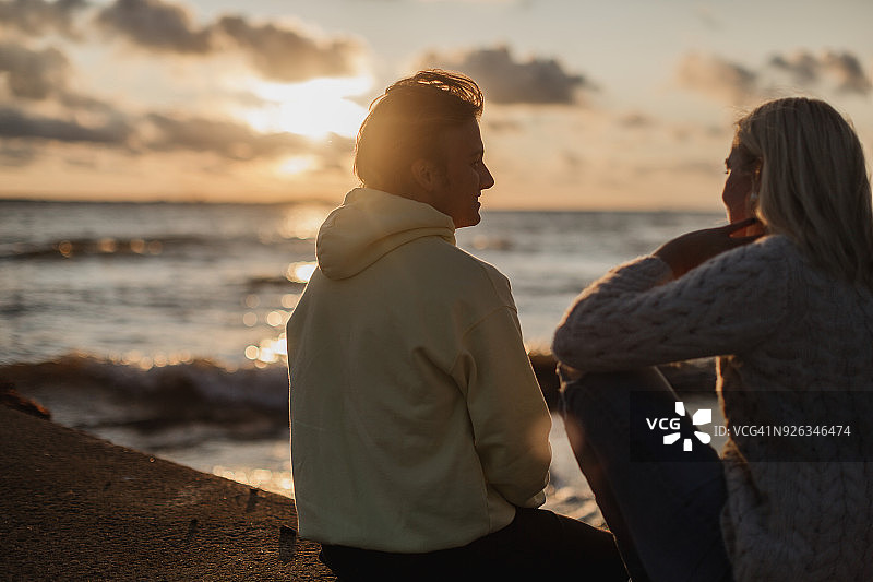 情侣坐在日落的海滩上图片素材