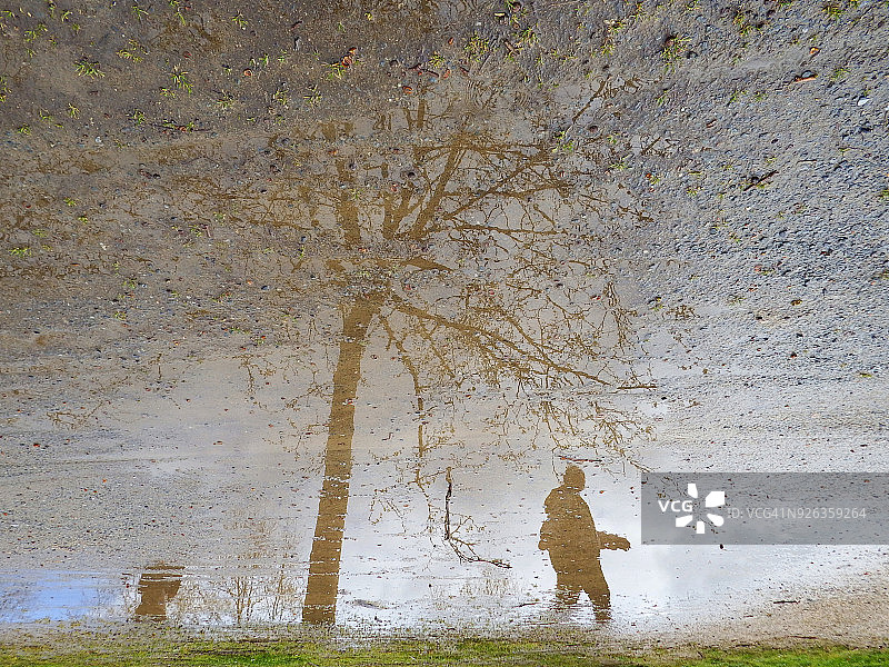 大雨过后，男人倒映在水坑里图片素材