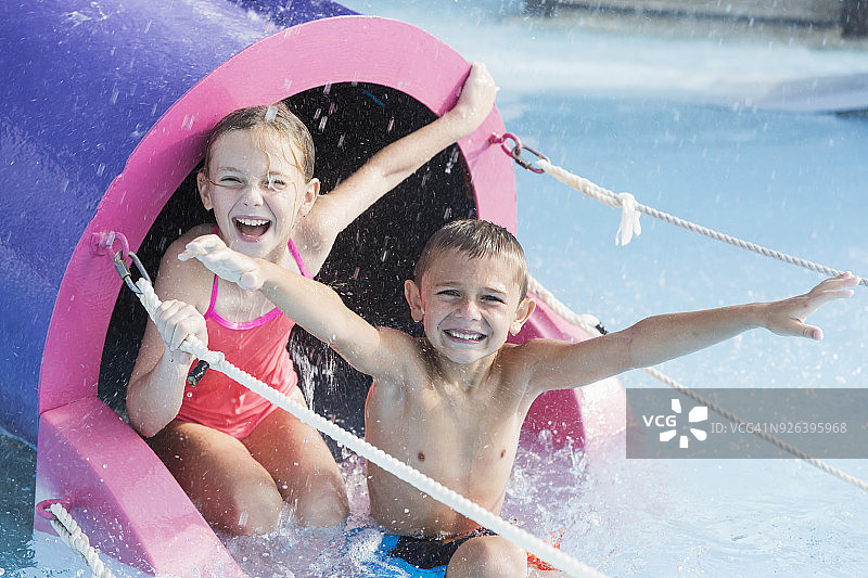 孩子们在水滑梯上对着镜头笑图片素材