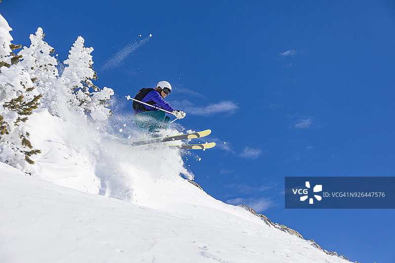 在西班牙加泰罗尼亚比利牛斯山脉巴奎拉贝雷特滑雪日，在厚厚的雪地里跳跃的女人图片素材