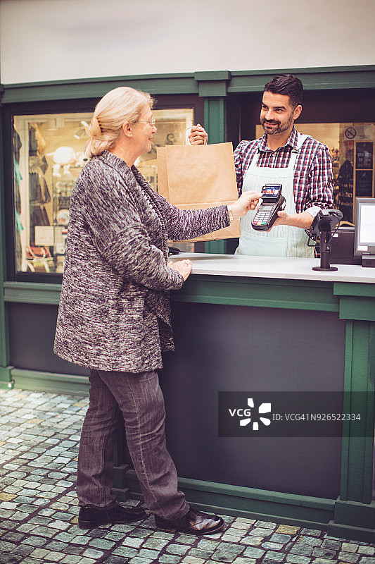 年长的妇女向收银员付款图片素材