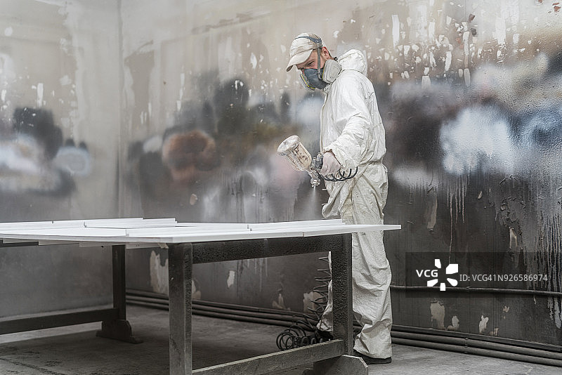 中年男子在小型工厂戴防护面罩喷漆图片素材