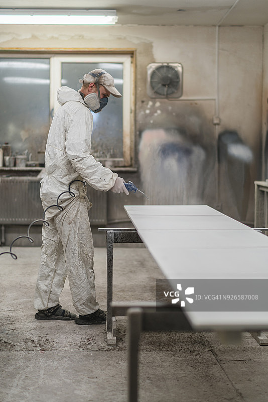 中年男子戴防护面罩和工作服，用压缩空气枪清洁表面图片素材