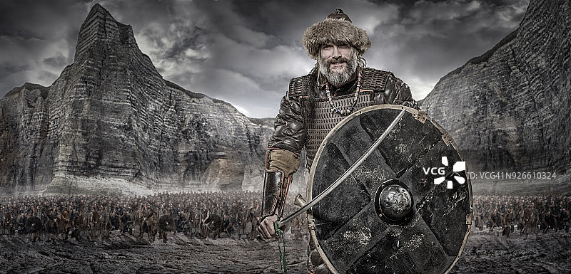 独自站在维京宝藏和山脉前的挥舞武器的维京战士图片素材