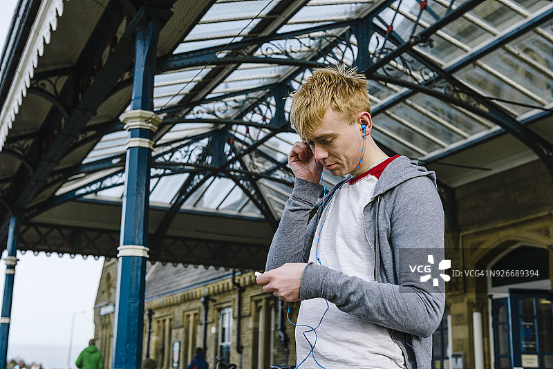 年轻男人在英国火车站外听音乐图片素材