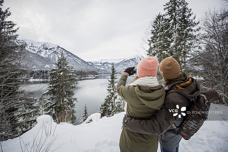 夫妇在高山冬季景观与湖泊拍照图片素材