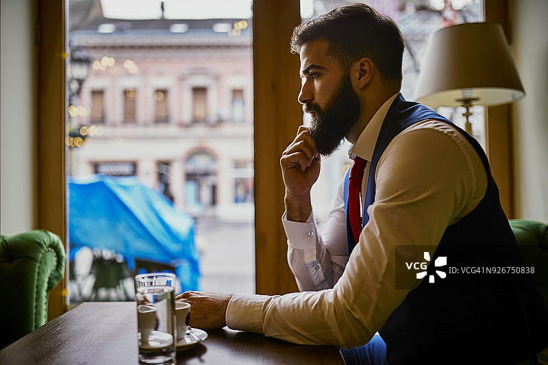 若有所思的时髦青年坐在咖啡馆里图片素材