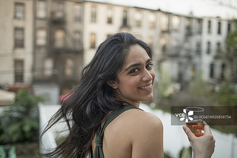 在聚会上拿着一杯葡萄酒的年轻女人图片素材