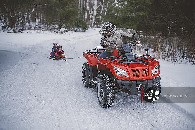 中年妇女驾驶四轮摩托车，拉着雪橇上的孩子们图片素材