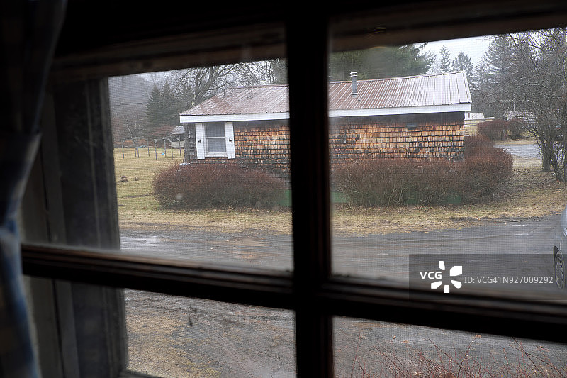 透过乡村小屋的窗户看冬日阴雨天的另一间小屋图片素材