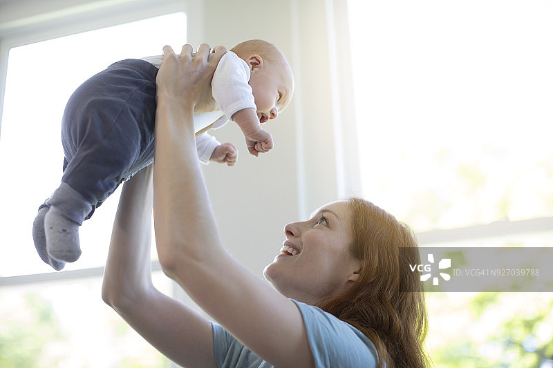 母亲对着窗户高举着新生婴儿图片素材
