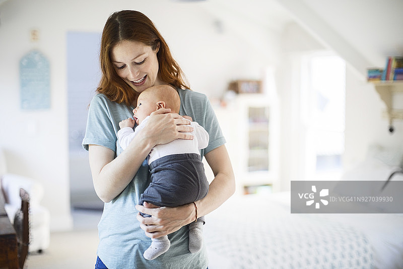快乐的红发女人在卧室里抱着儿子图片素材