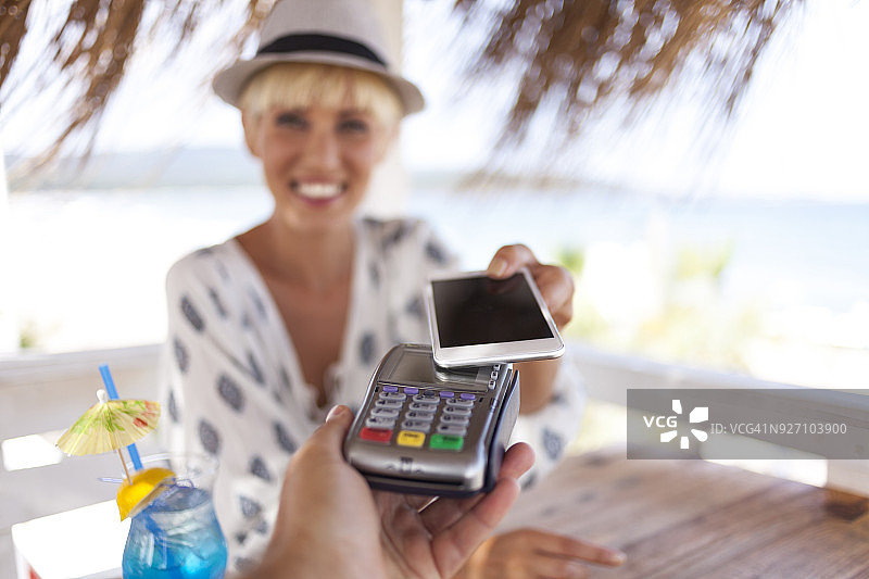 用智能手机进行移动支付的金发女人图片素材