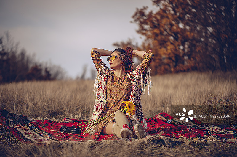坐在田野里的年轻嬉皮士女人图片素材