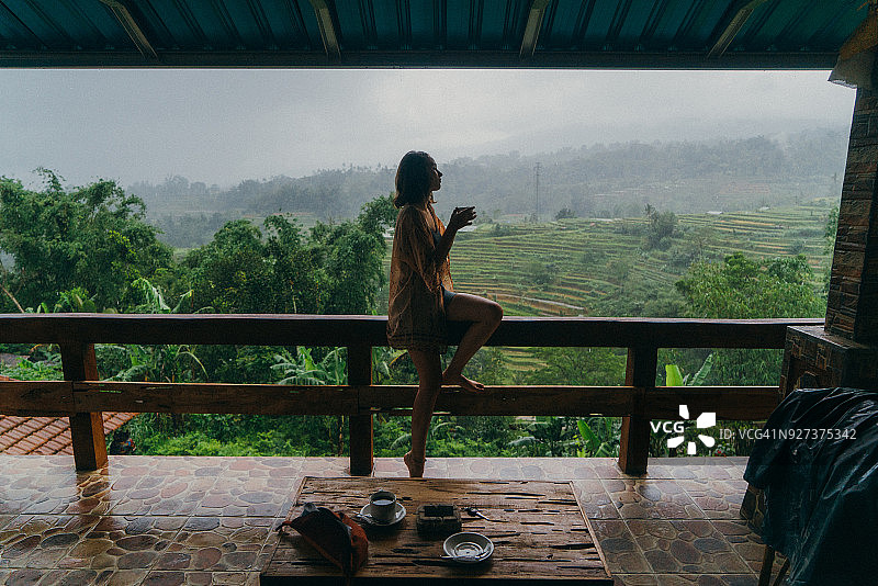 在阳台上喝茶，欣赏稻田景色的女人图片素材