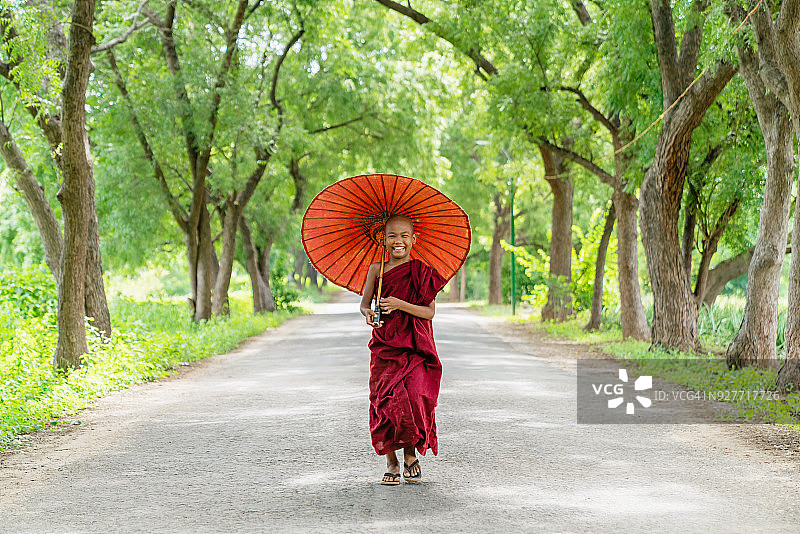 微笑的年轻僧侣在缅甸蒲甘的绿色小巷里图片素材