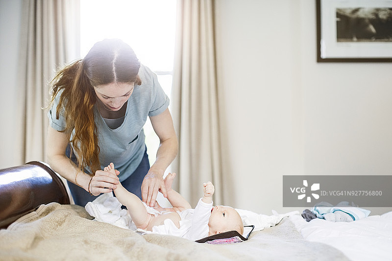 女人在床上为新生婴儿换尿布图片素材