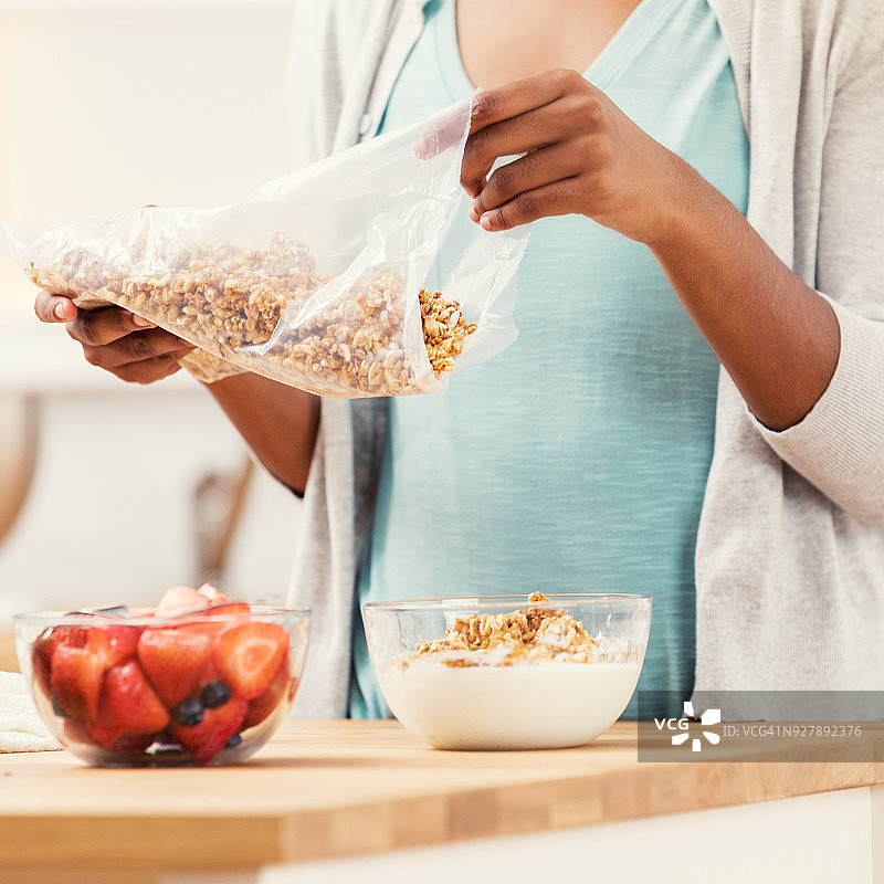 正在倾倒含水果早餐谷物的女性图片素材