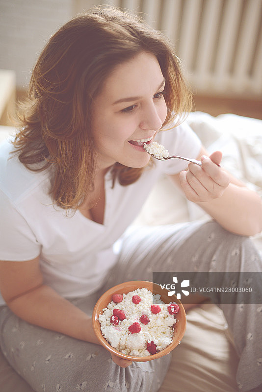 在卧室里吃农家奶酪的年轻女人图片素材