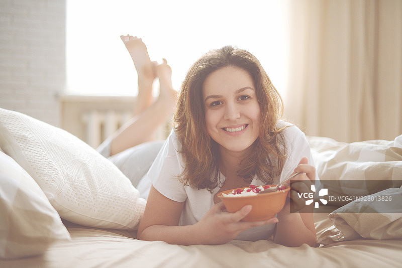在卧室里吃农家奶酪的年轻女人图片素材