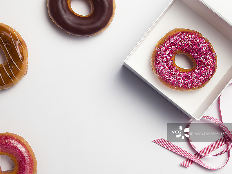 装有钻石粉色甜甜圈的粉色丝带白色盒子图片素材