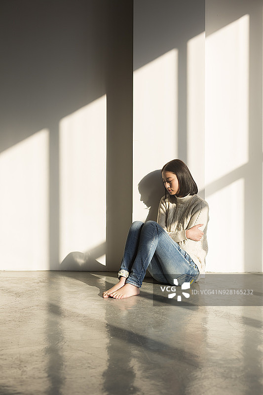 女孩坐在地板上拥抱自己图片素材