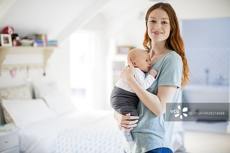 家中，笑容满面的母亲拥抱新生儿子图片素材