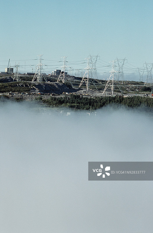 加拿大魁北克省詹姆斯湾雾蒙蒙的山顶上的电力线图片素材