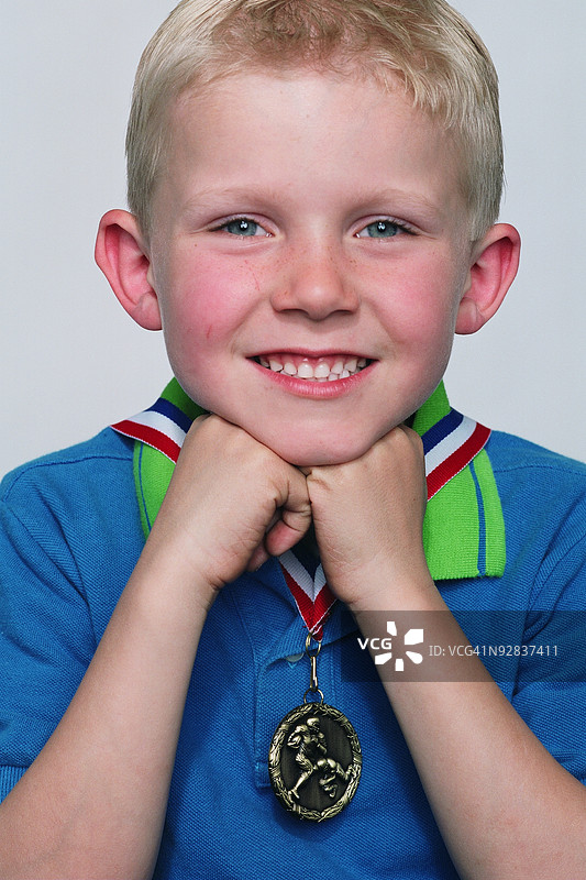 男孩佩戴奖牌为相机摆姿势图片素材