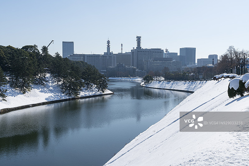 东京千代田区冬日暴风雪后的早晨——2018年1月23日,霞关地区和日比谷地区的摩天大楼矗立在白雪皑皑的皇宫护城河后,倒映在护城河水面上图片素材