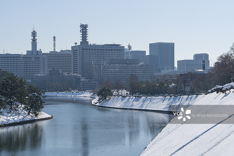 东京千代田区冬日暴风雪后的早晨——2018年1月23日，霞关地区和日比谷地区的摩天大楼矗立在白雪皑皑的皇宫护城河后，倒映在护城河水面上图片素材