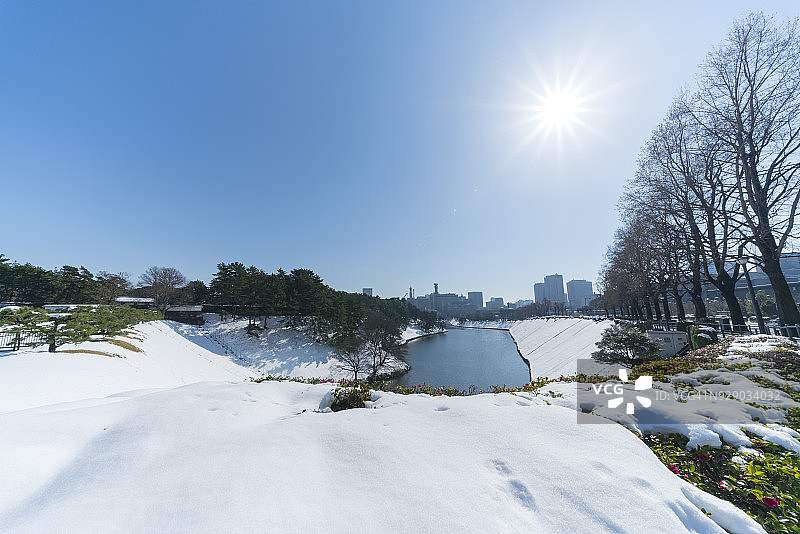 1月23日东京千代田区冬日暴风雪后的清晨，霞关和永田町高层建筑矗立在被白雪覆盖的皇居护城河后，倒映在护城河水面上图片素材