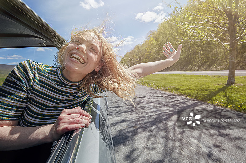 女人开车时将头伸出窗外图片素材