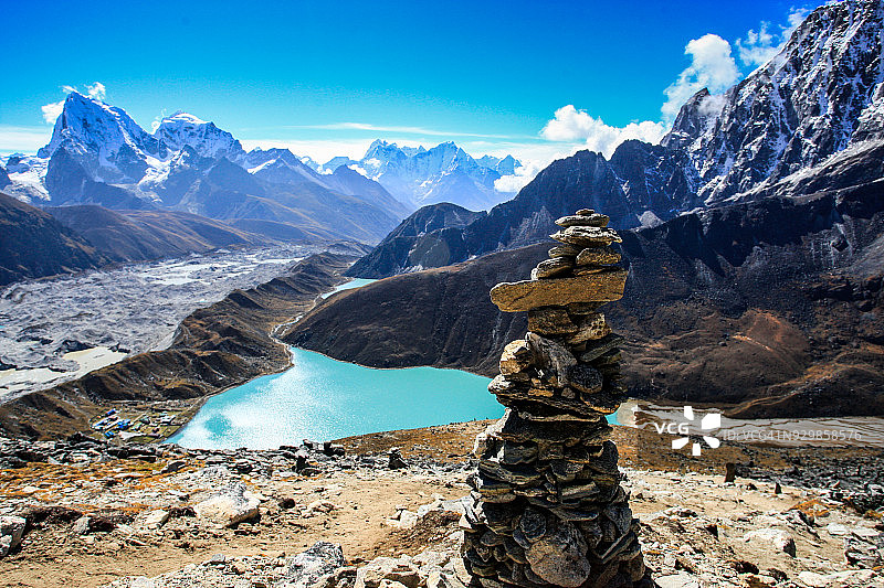 碧绿色湖泊前方的叠石与雪山图片素材