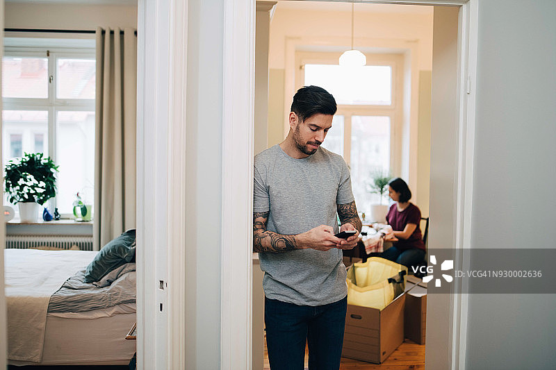 中年男人靠在新家门口使用手机图片素材